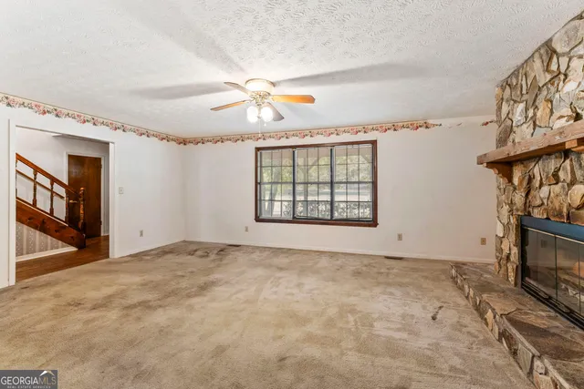 a view of an empty room with window and fireplace