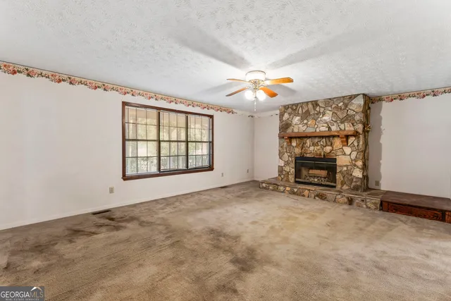 an empty room with windows and fireplace