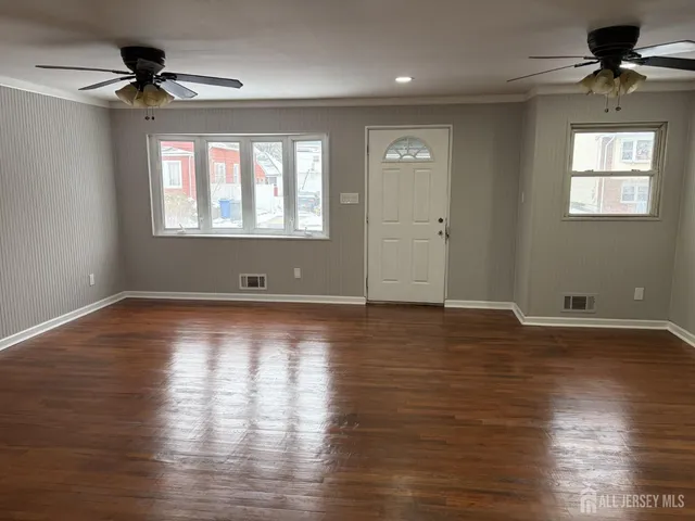 a view of an empty room with a window and wooden floor