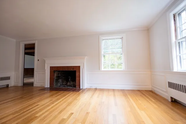 an empty room with wooden floor a fireplace and windows