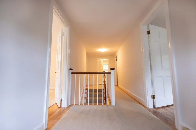a view of a hallway with wooden floor and stairs