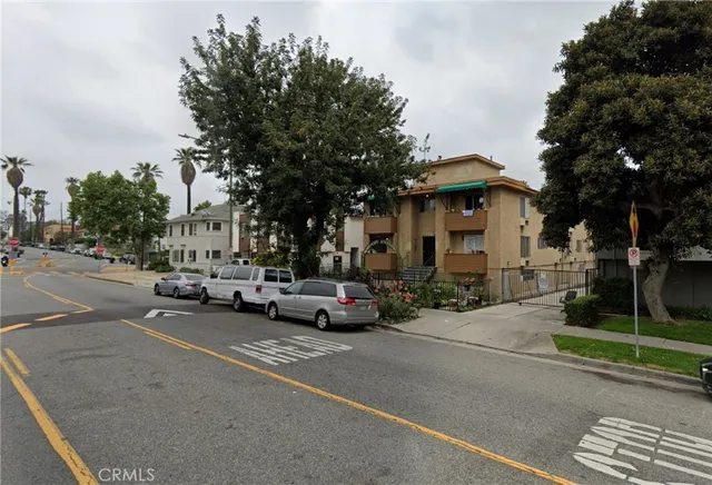 a view of road with card parked on side and retail shops