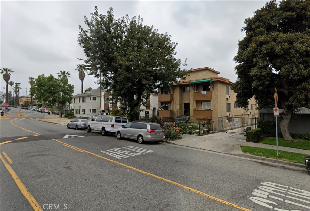 a view of road with card parked on side and retail shops