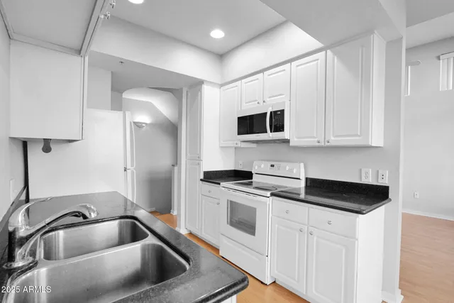 a kitchen with white cabinets a sink and white appliances