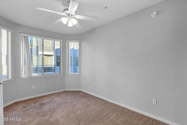an empty room with windows and ceiling fan