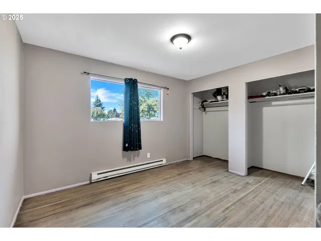 a view of an empty room with window and wooden floor