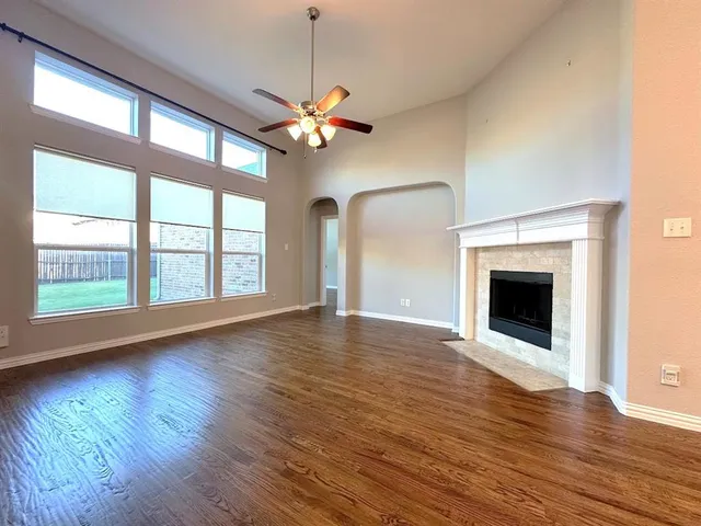 a view of an empty room with wooden floor fireplace and a window