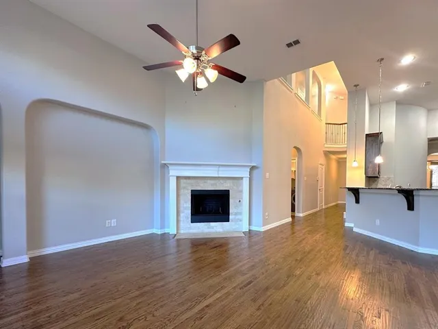 a view of an empty room with wooden floor and a fireplace