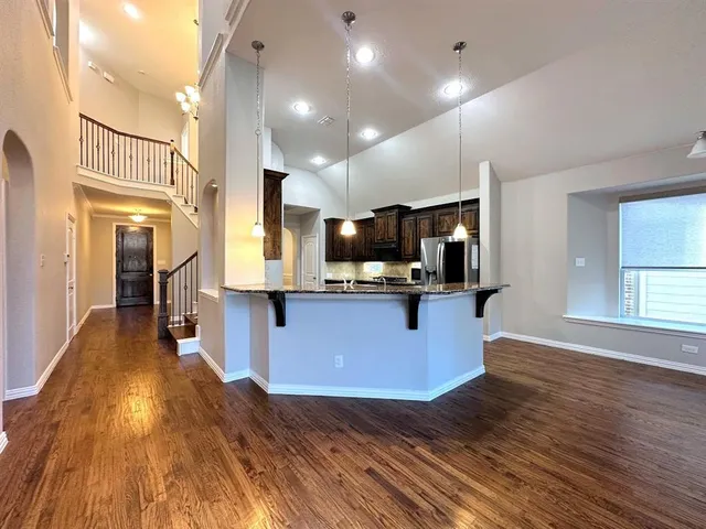 a large kitchen with stainless steel appliances granite countertop a large counter top a stove and a wooden floors