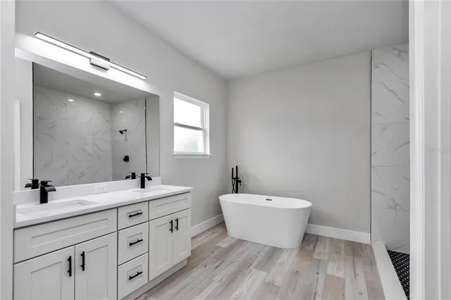 a spacious bathroom with a double vanity sink mirror and bathtub