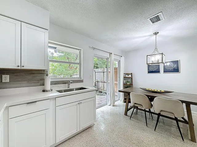 a kitchen that has a sink a chair in it and wooden floors