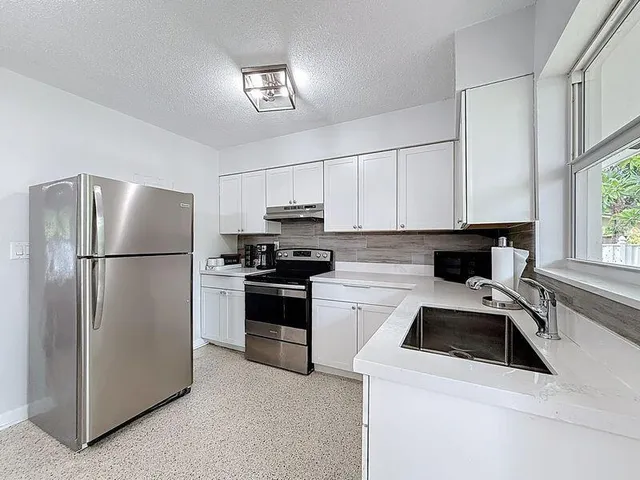 a kitchen with a refrigerator sink and cabinets