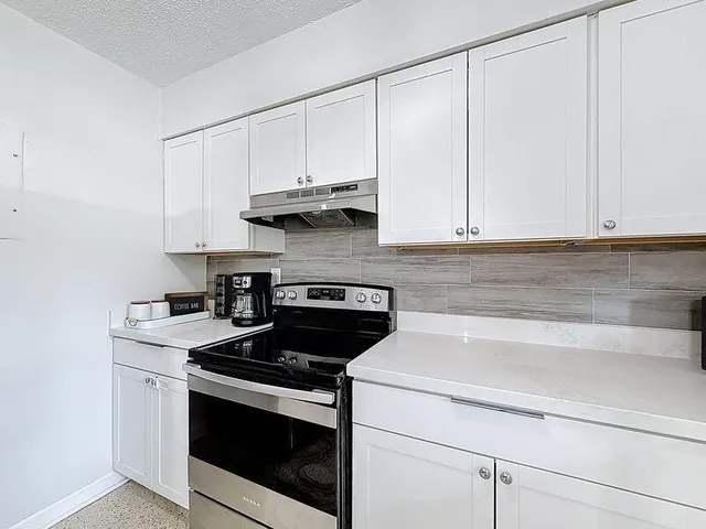 a kitchen with granite countertop white cabinets and white appliances