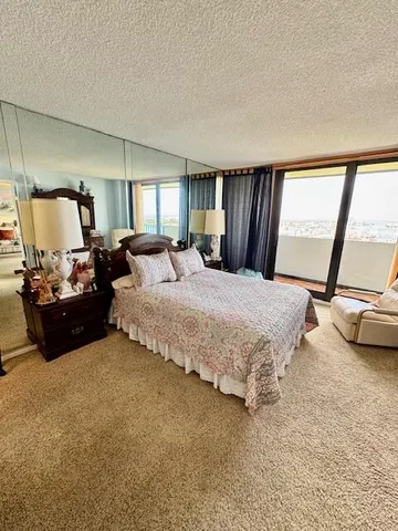 a spacious bedroom with a bed a couch and large window