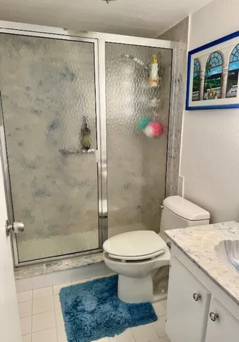 a bathroom with a granite countertop toilet a sink and shower