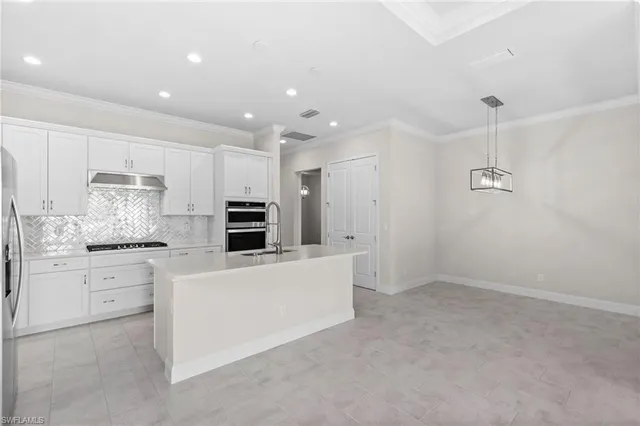 a kitchen with kitchen island a sink stainless steel appliances and white cabinets