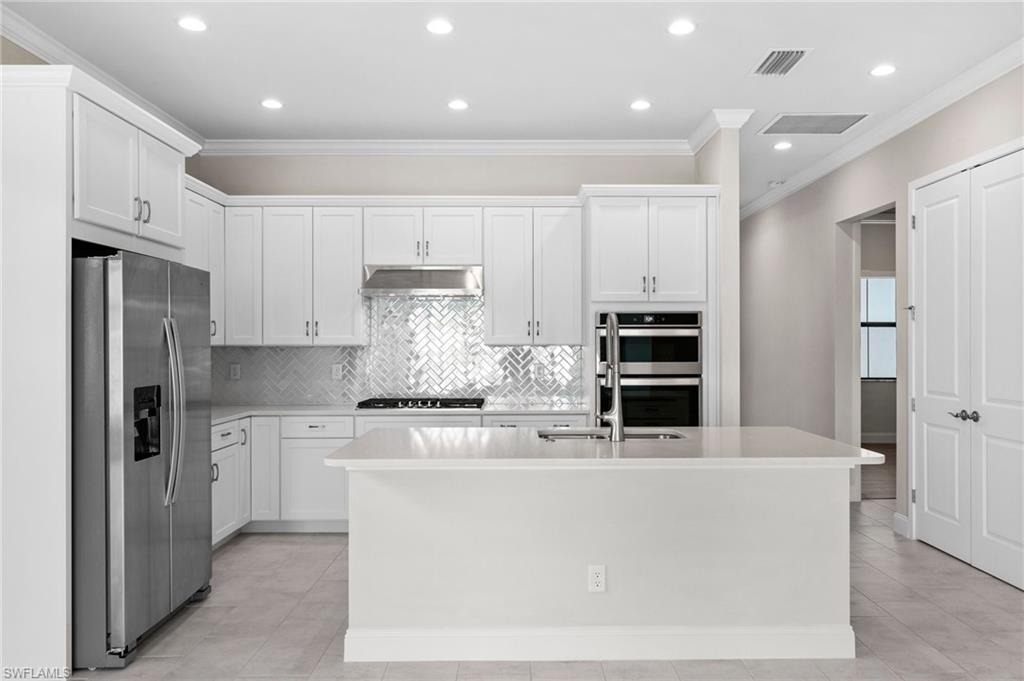 14756 Kingfisher Loop Naples, FL 34120 - Photo 6 of 31 a kitchen with cabinets and stainless steel appliances