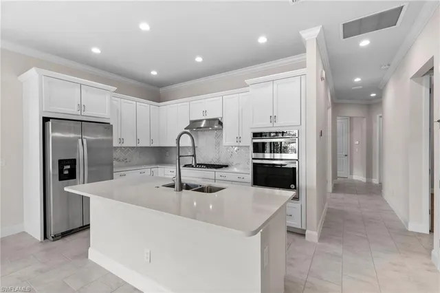 a kitchen with kitchen island stainless steel appliances a sink and a refrigerator