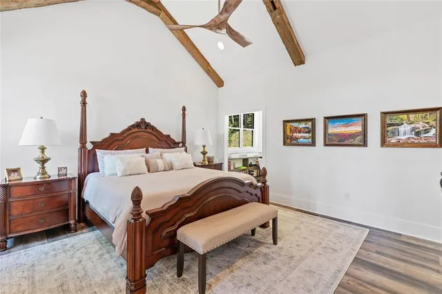 a bedroom with a bed a dresser and potted plants with the wooden floor