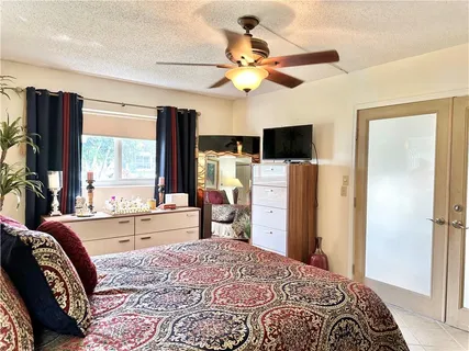 a bedroom with a bed dresser and a large window