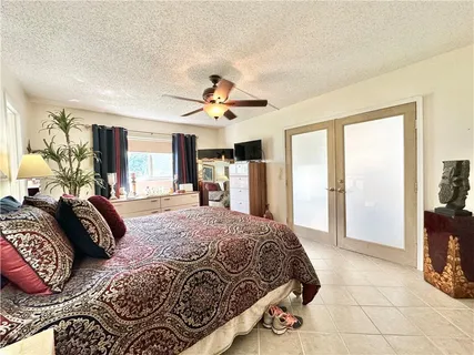a spacious bedroom with a large bed a chandelier and windows