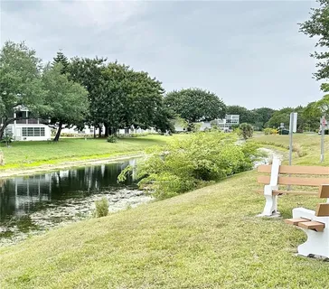 a view of a lake with a yard and large trees