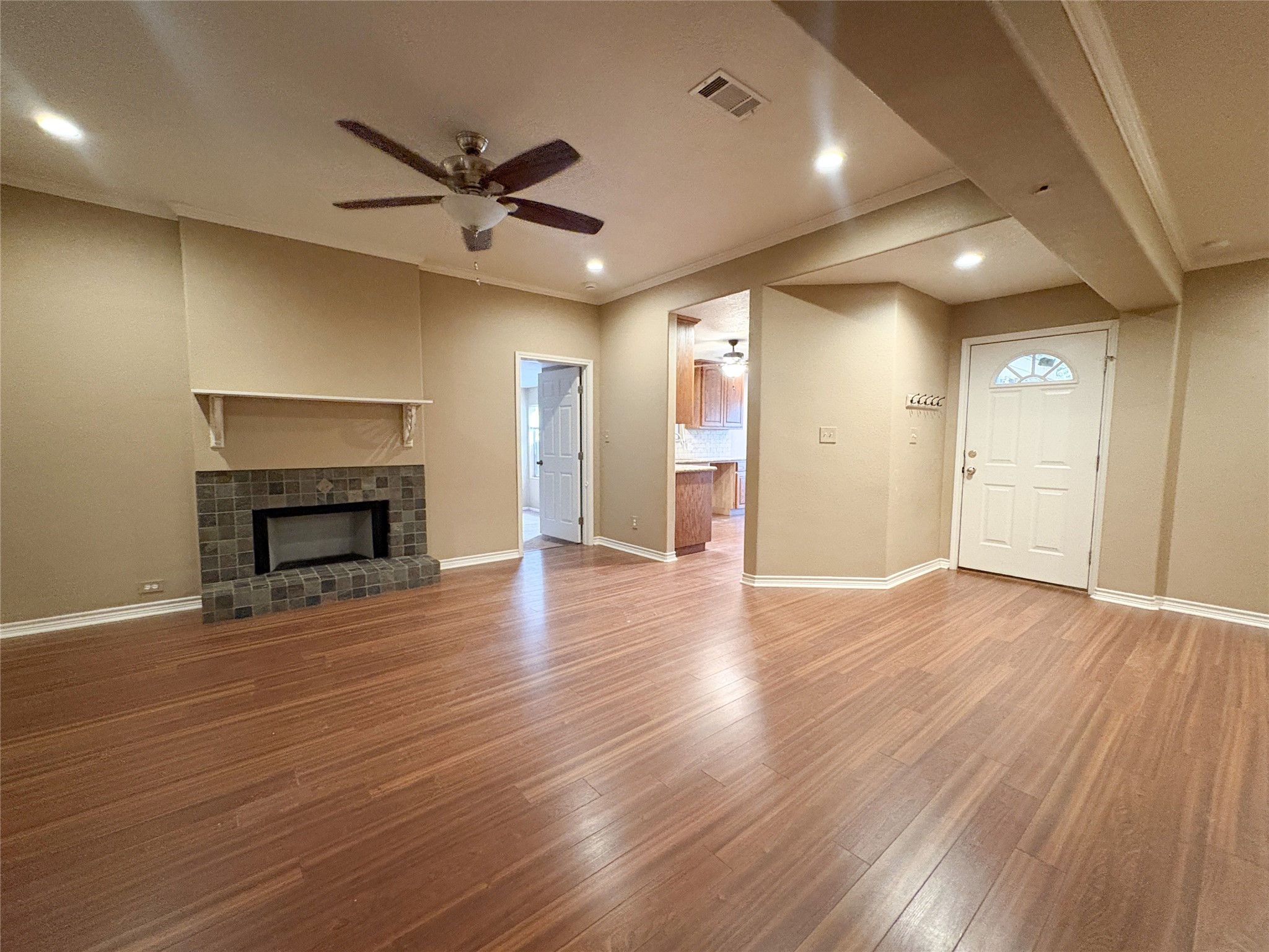 4503 Rattan Avenue Bay City, TX 77414 - Photo 2 of 14 Spacious living area with elegant wood flooring, a cozy fireplace, and recessed lighting, leading to a bright kitchen with modern finishes.