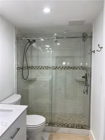a bathroom with a granite countertop shower a toilet and sink