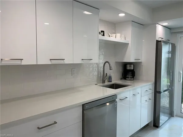 a kitchen with granite countertop a sink a stove and refrigerator