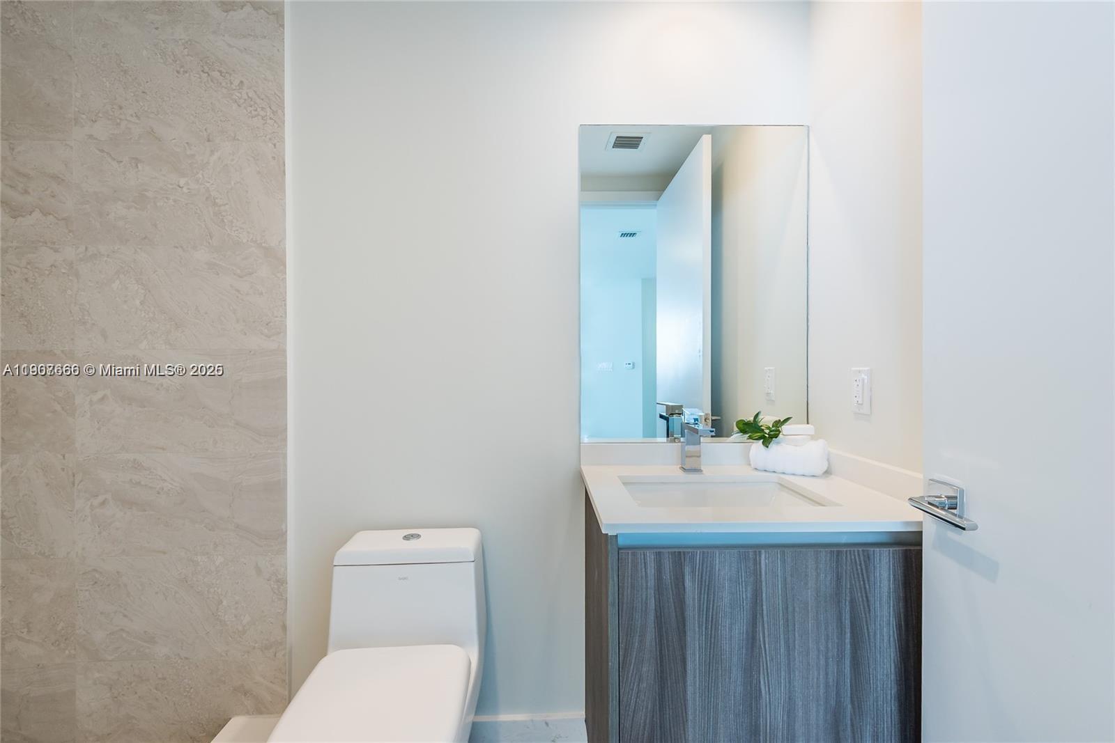 488 Northeast 18th Street, Unit 1815 Miami, FL 33132 - Photo 30 of 31 a bathroom with a toilet a sink and mirror