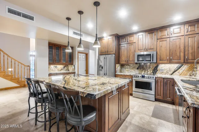 a kitchen with stainless steel appliances granite countertop a kitchen island a stove a table and chairs