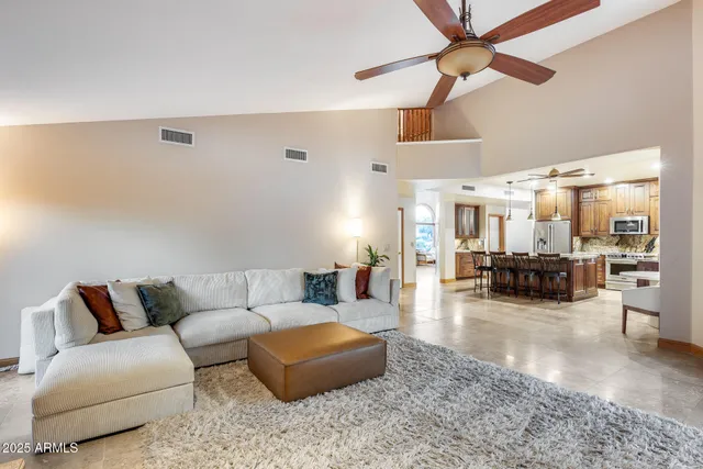 a living room with furniture kitchen view and a chandelier