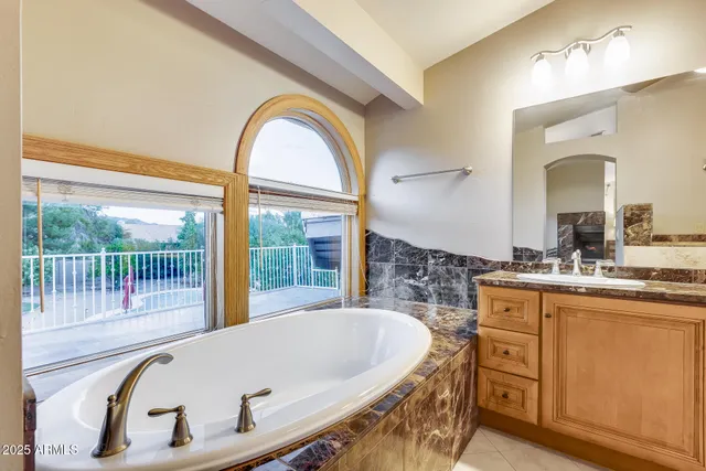 a bath tub sitting next to a bathroom sink and a large mirror