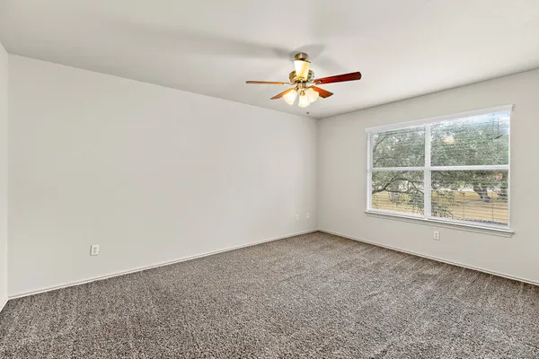 an empty room with a window and a ceiling fan