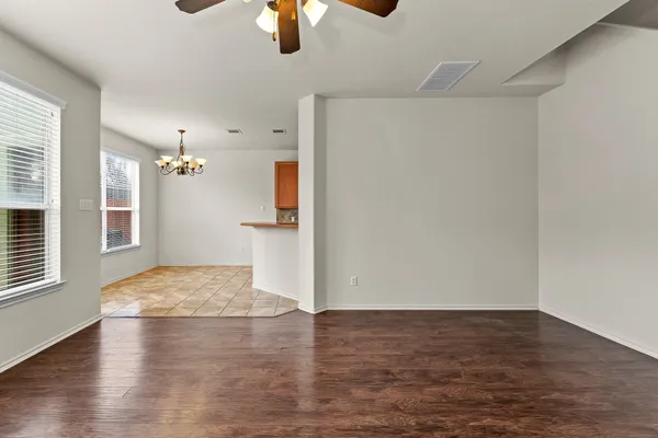 a view of empty room with wooden floor and fan