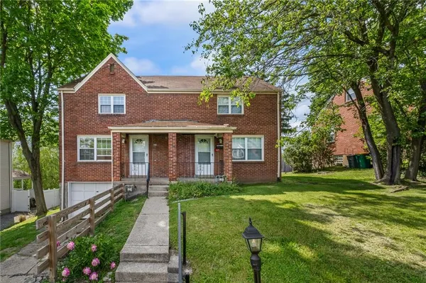a front view of a house with a yard and trees