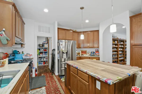 a kitchen with stainless steel appliances kitchen island granite countertop a table chairs in it and wooden floors