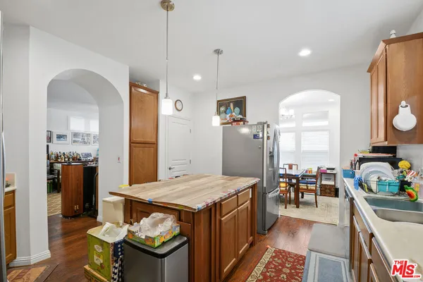 a living room with stainless steel appliances furniture a rug and a kitchen view