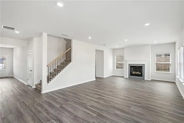 a view of an empty room with wooden floor fireplace and a window