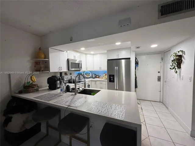 a kitchen with stainless steel appliances granite countertop a table chairs sink refrigerator and cabinets