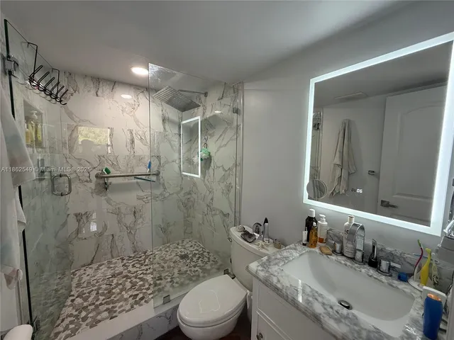 a bathroom with a granite countertop sink toilet a mirror a vanity and shower