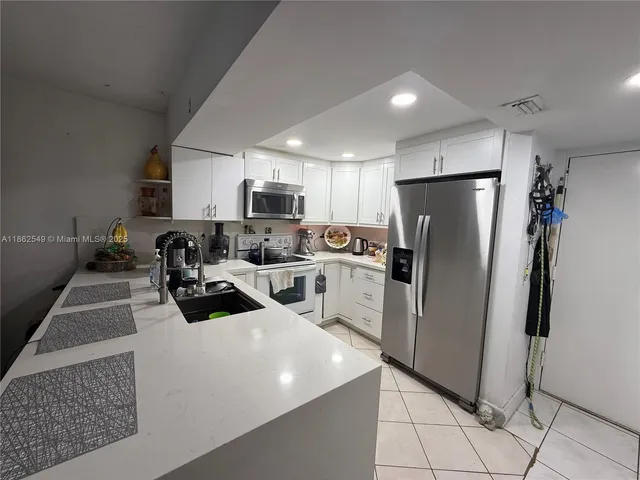 a kitchen with refrigerator a microwave a sink and cabinets