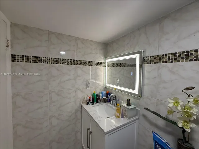 a bathroom with a sink vanity granite and a shower