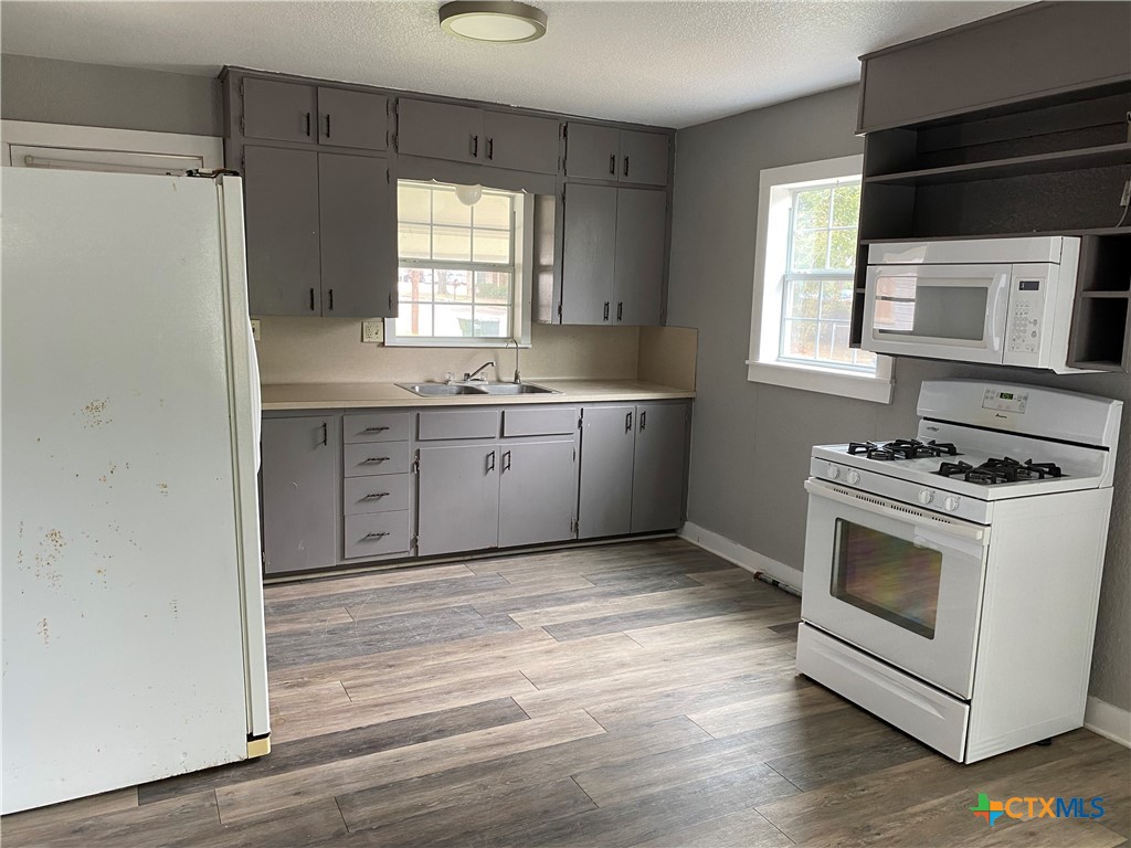121 Fifteenth Street East Shiner, TX 77984 - Photo 7 of 17 a kitchen with granite countertop a stove a sink and a microwave
