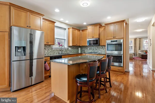 a hall with cabinets a sink and a wooden floor