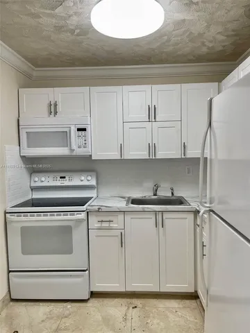 a kitchen with white cabinets and white appliances