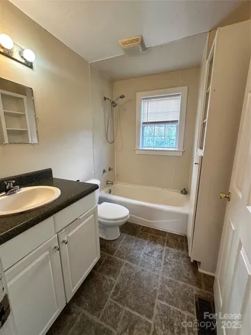 a bathroom with a granite countertop sink toilet a mirror and a tub