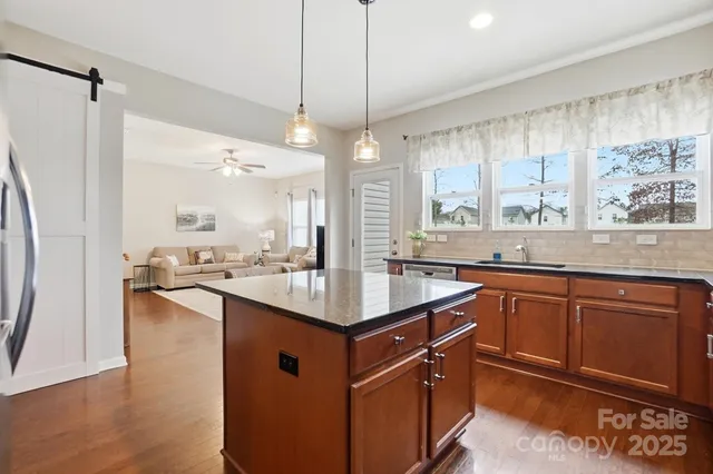 a kitchen with stainless steel appliances granite countertop a sink a counter space and a window