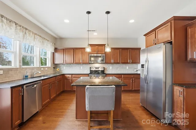 a kitchen with stainless steel appliances granite countertop a stove a sink island and a refrigerator
