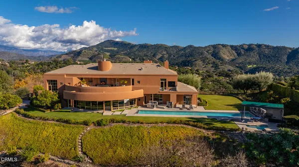 an aerial view of a house with swimming pool a patio and mountain view